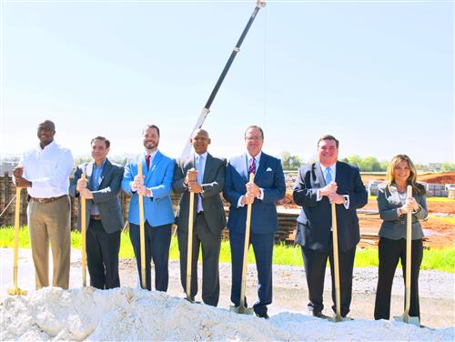 Board members and superintendent standing with shovels at construction site 